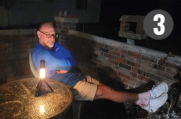 Man relaxing on a porch next to a BuzzDefense Portable with its light turned on